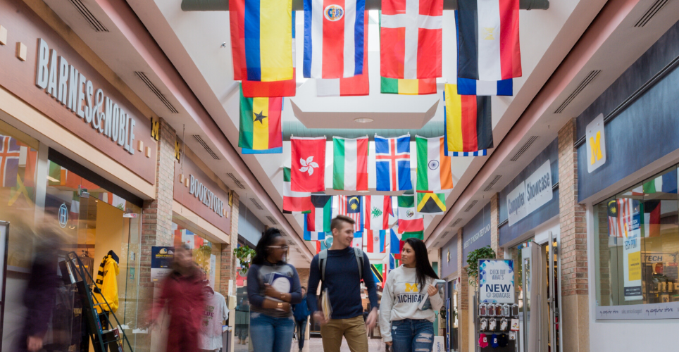 People walking through a hallway with flags from different countries