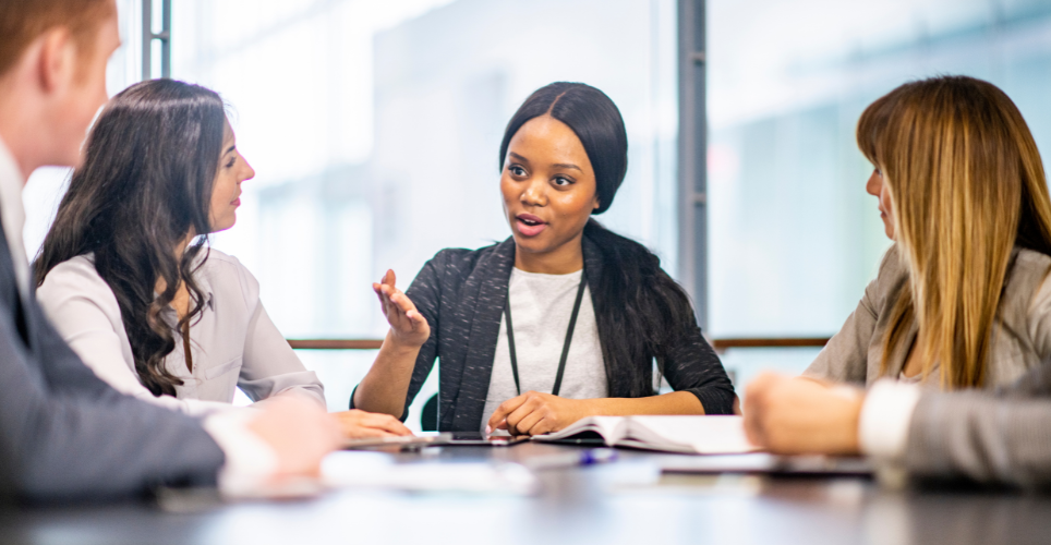 woman leading a team around a conference table at work