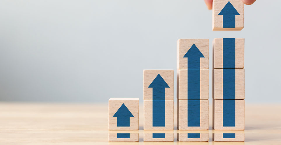 Close up of 4 wooden blocks with arrows pointed upward on a wooden table