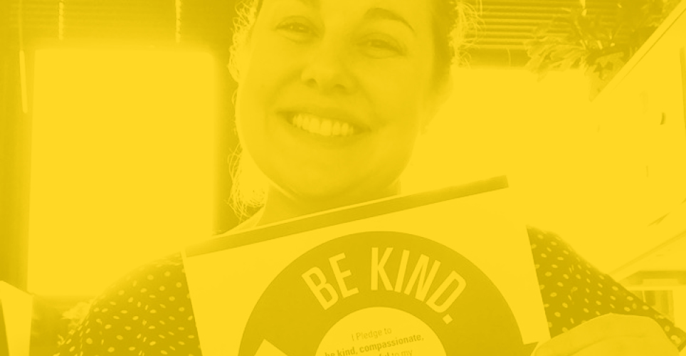 Yellow tinted image of woman smiling holding kindness pledge