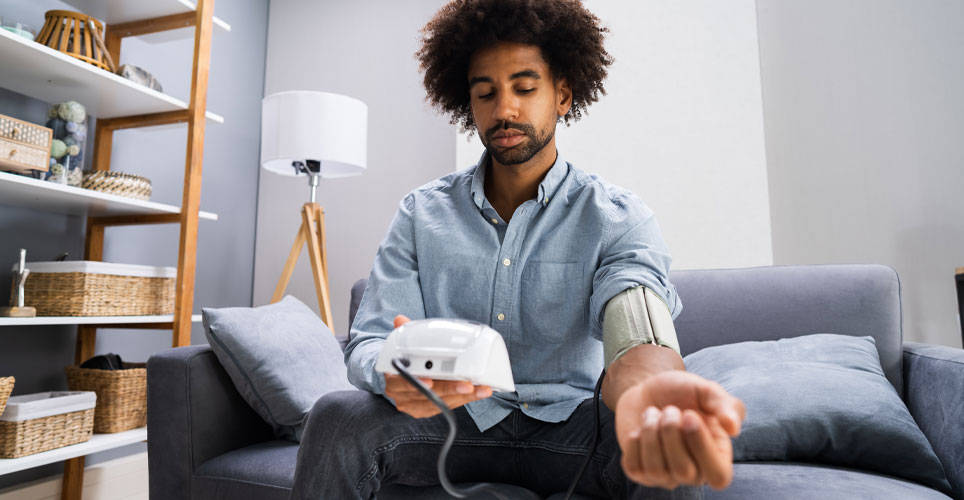 Black man taking his blood pressure in a living room