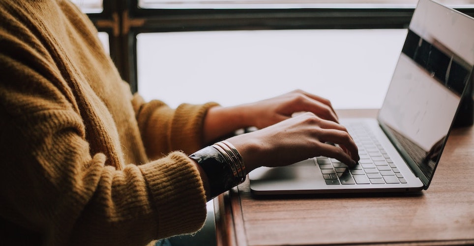 woman sitting at a desk with her hands on a laptop keyboard