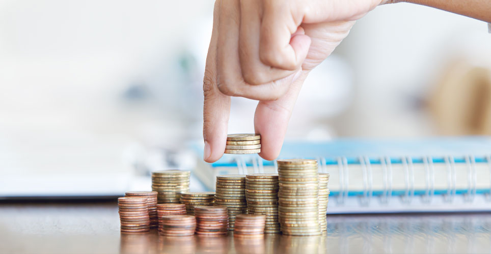 Close up of a hand putting coins on top of a pile with other piles in a line