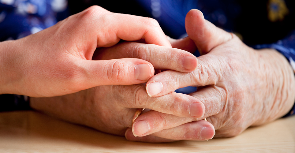 Hand holding an elderly loved one's hands