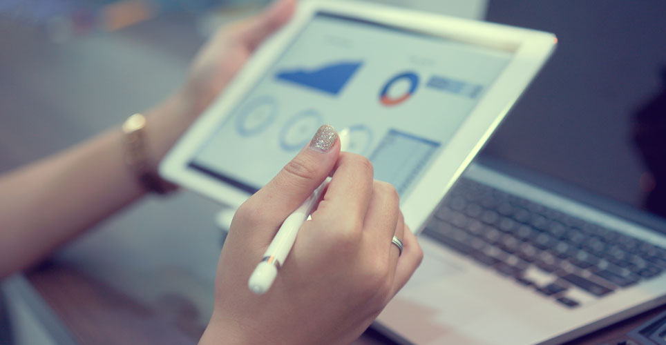 Close up of two white hands holding an iPad with a stylus in one hand and graphics on the screen