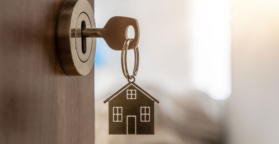 Close up of a key with a dangling home charm in a door lock