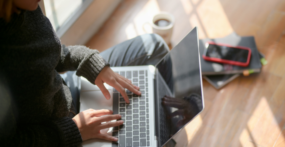 Person sitting on floor working on laptop