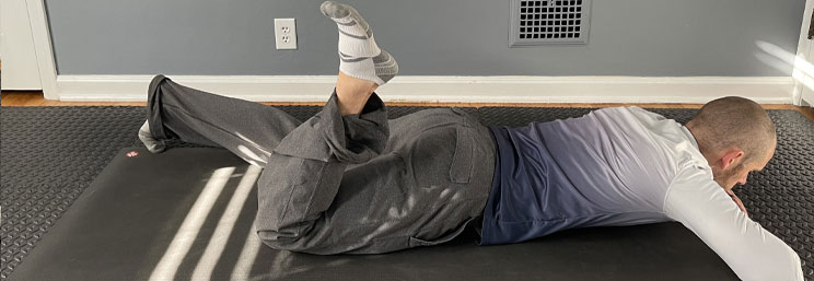 man laying on ground on stomach with on leg bent