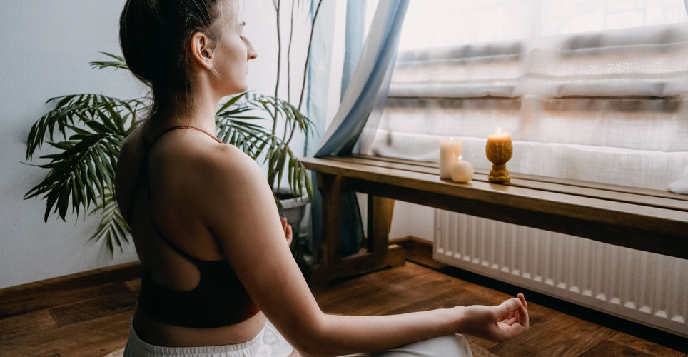 Close up of a White woman meditating in front of a window in her home.