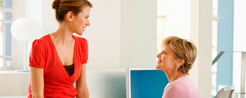 two women talking at desk