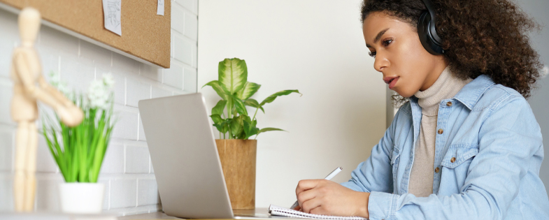 Woman on computer with headphones.