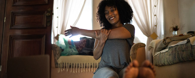 woman stretching at home in front of a laptop