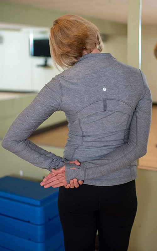 woman standing facing away from camera showing the neck and upper trapezius release end movement