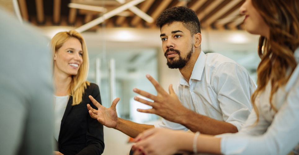 Man sitting with coworkers talking.