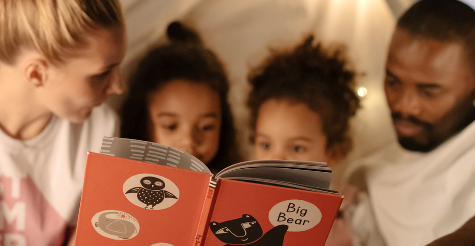 family reading together, two adults and two children.