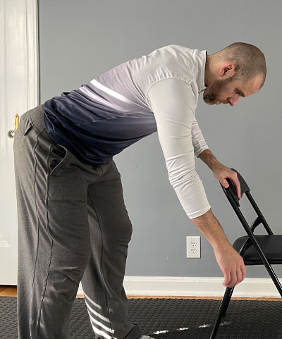 man with one hand on chair leaning over