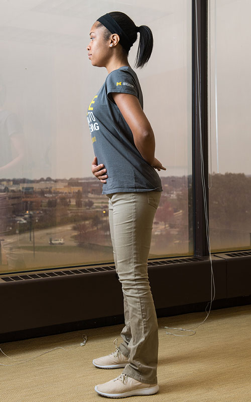 Young woman standing showing start of postural correction movement