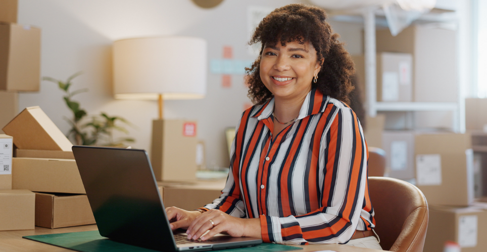 Woman sitting at her desk surrounded by shipping boxes