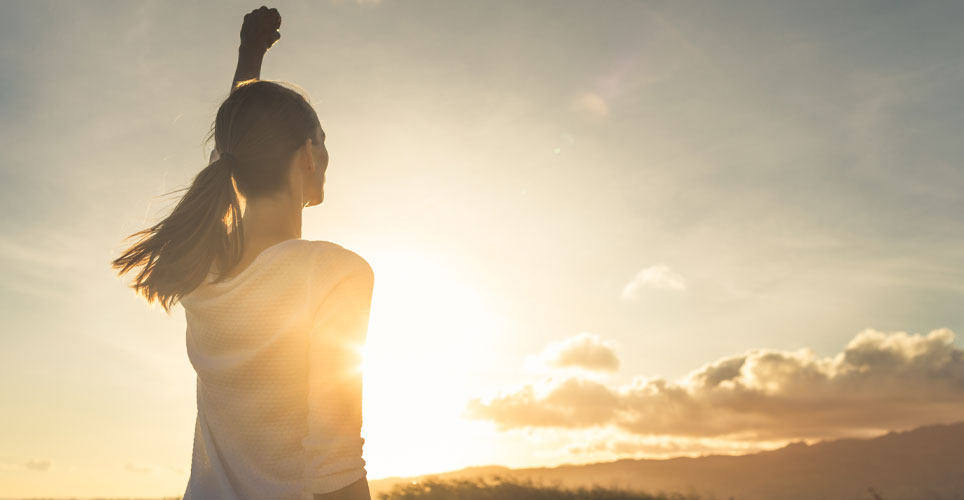 women with raised fist at sunset/sunrise