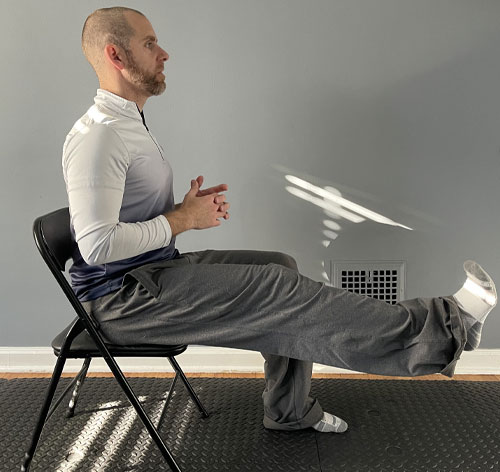 man sitting in chair with one leg raised