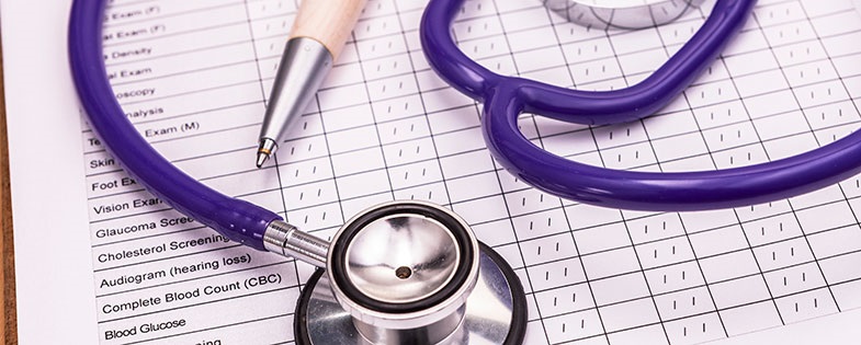 Purple stethoscope and pen on medical paperwork