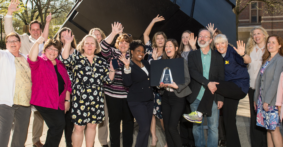 The team recipients of the 2018 President's Staff Innovation Award celebrate by the cube.