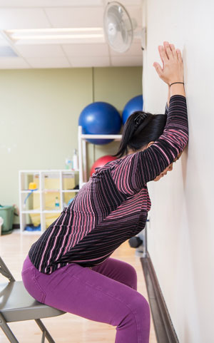 woman sitting in chair leaning forward with arms on a wall