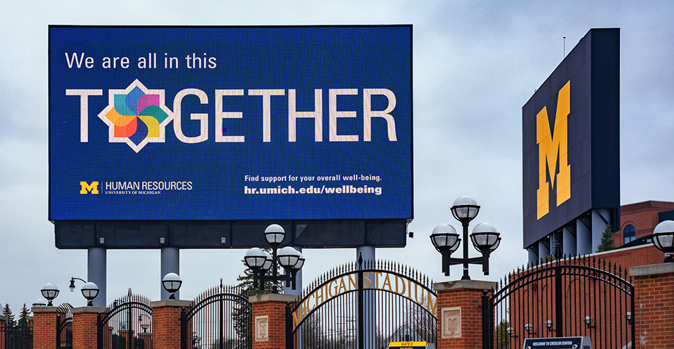 Billboard featuring Michigan's model of well-being outside Michigan Stadium