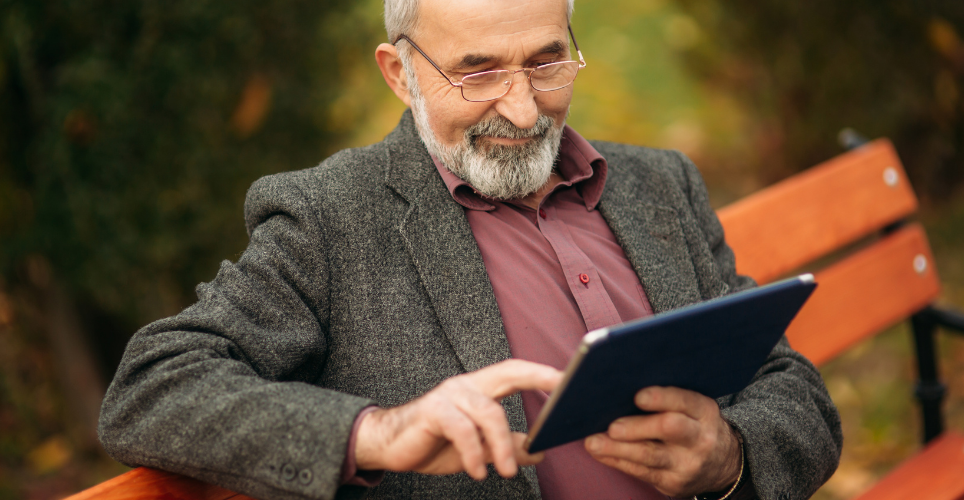 Man sitting on a bench looking at an iPad.