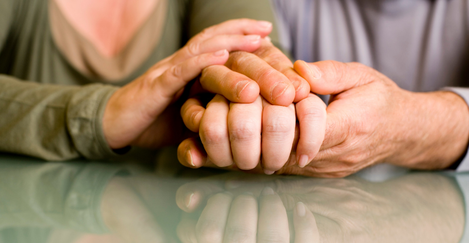 close up of two White hands clasped on a table or desk