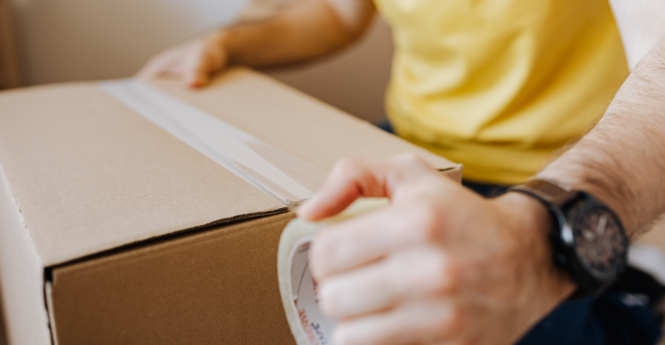 Man taping up cardboard box.