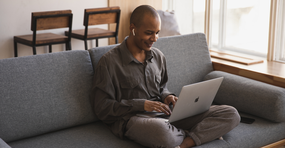 Person sitting on couch typing on laptop.