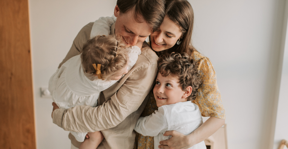 Two parents hugging their two small children. 