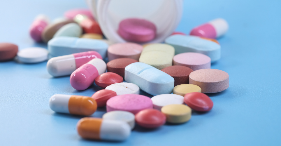 Colorful pills spilling from a medicine bottle on a blue background.