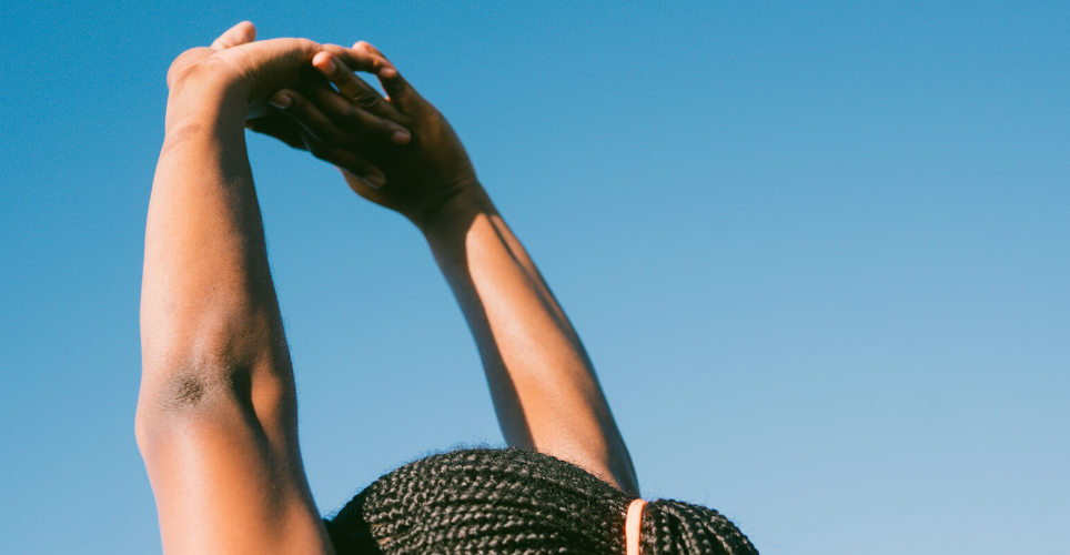 Shot of Black woman stretching her arms above her head from the crown of her head up