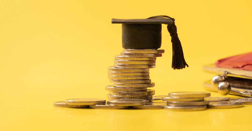 Stack of gold coins with a graduate cap sitting on the top. 