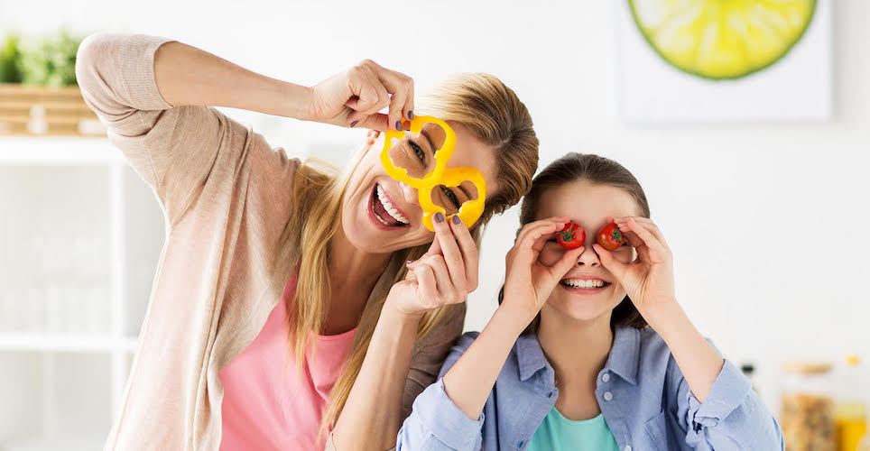 Mom and daughter in kitchen having fun with veggies